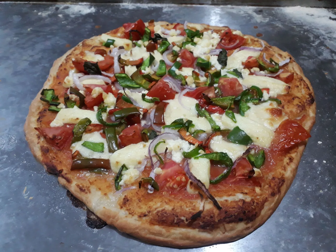 Pizza vegetariana con tomate, cebolla morada, pimiento verde y queso