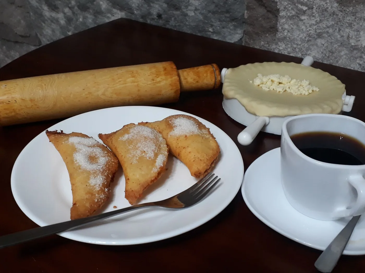 Empanadas de viento espolvoreadas con azúcar, con una taza de café