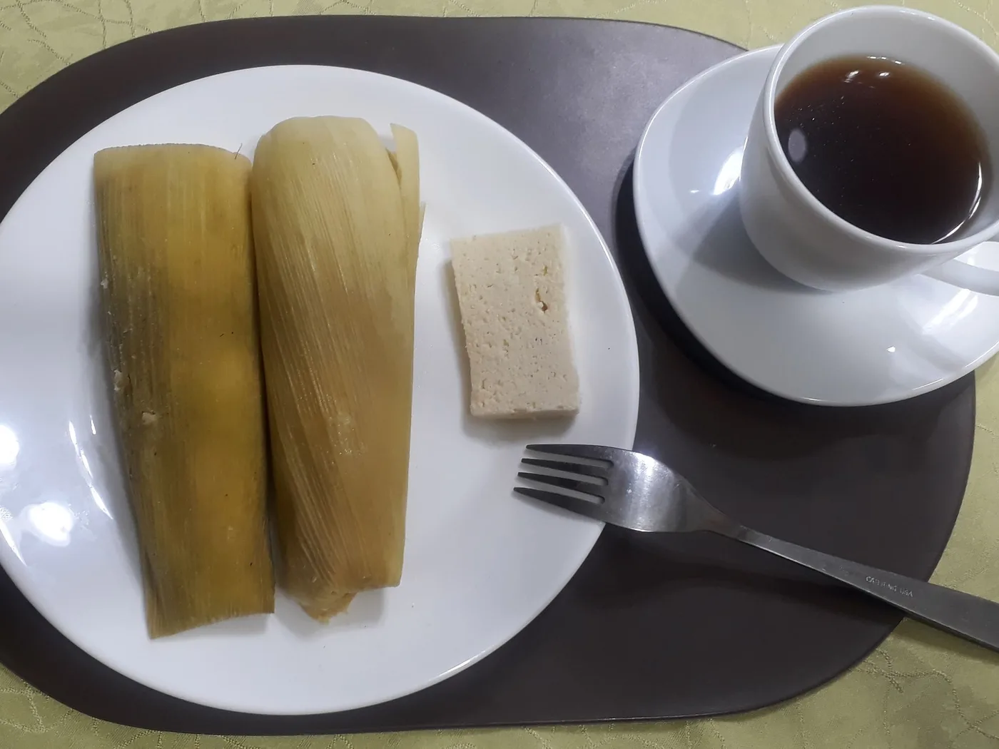 Dos humitas en hoja de choclo con queso fresco y una taza de café